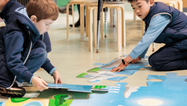 Two primary school children putting together an oversized jigsaw puzzle