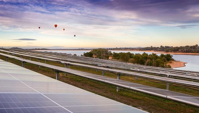 Winneke Solar Farm: hot air balloons hover over an array of solar panels next to Sugarloaf Reservoir at dawn