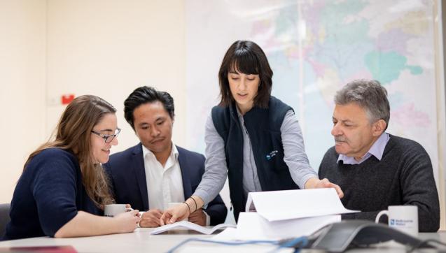 four office workers viewing a report
