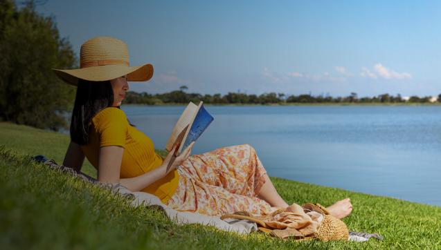 A lady relaxing with a book by her local waterway