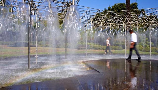 People walking through public water fountain