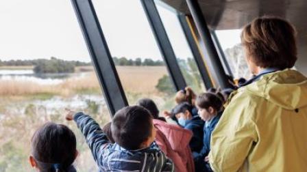 A group of children are looking out the bay windows into the Edithvale Wetlands