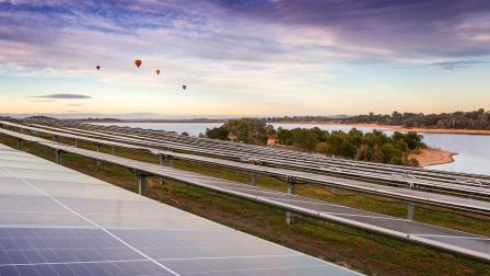 Winneke Solar Farm: hot air balloons hover over an array of solar panels next to Sugarloaf Reservoir at dawn