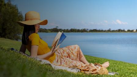 A lady relaxing with a book by her local waterway